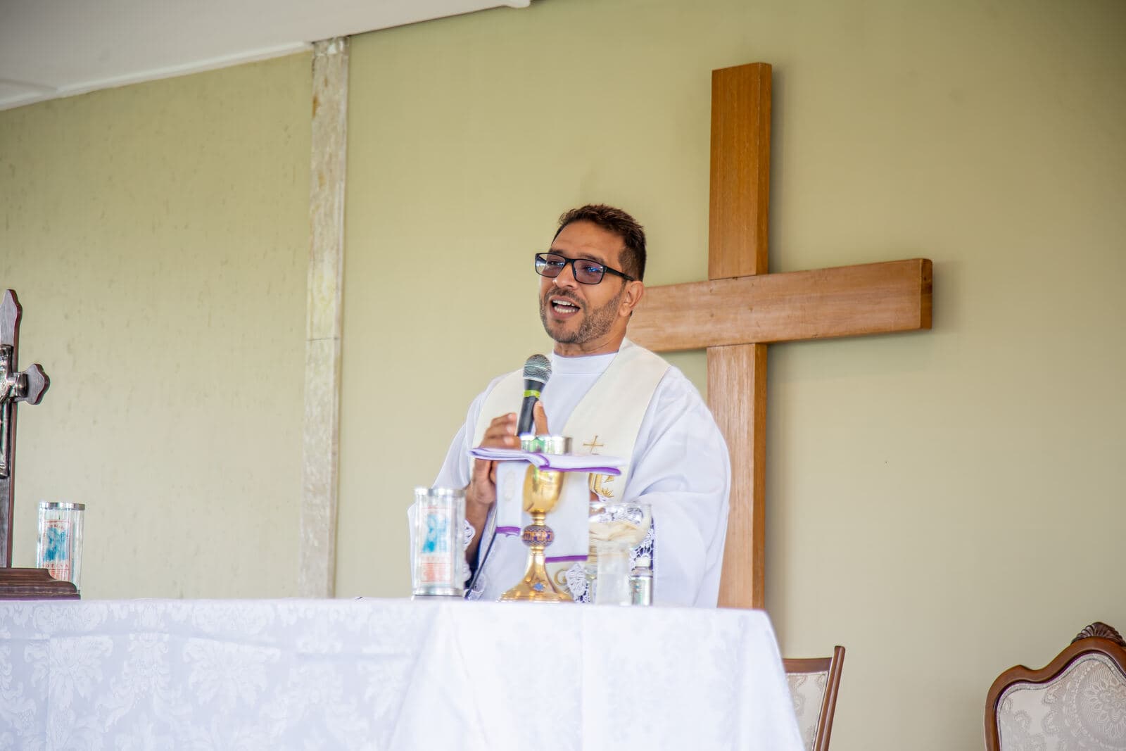 Padre sorridente durante a missa de Dia das Mães
